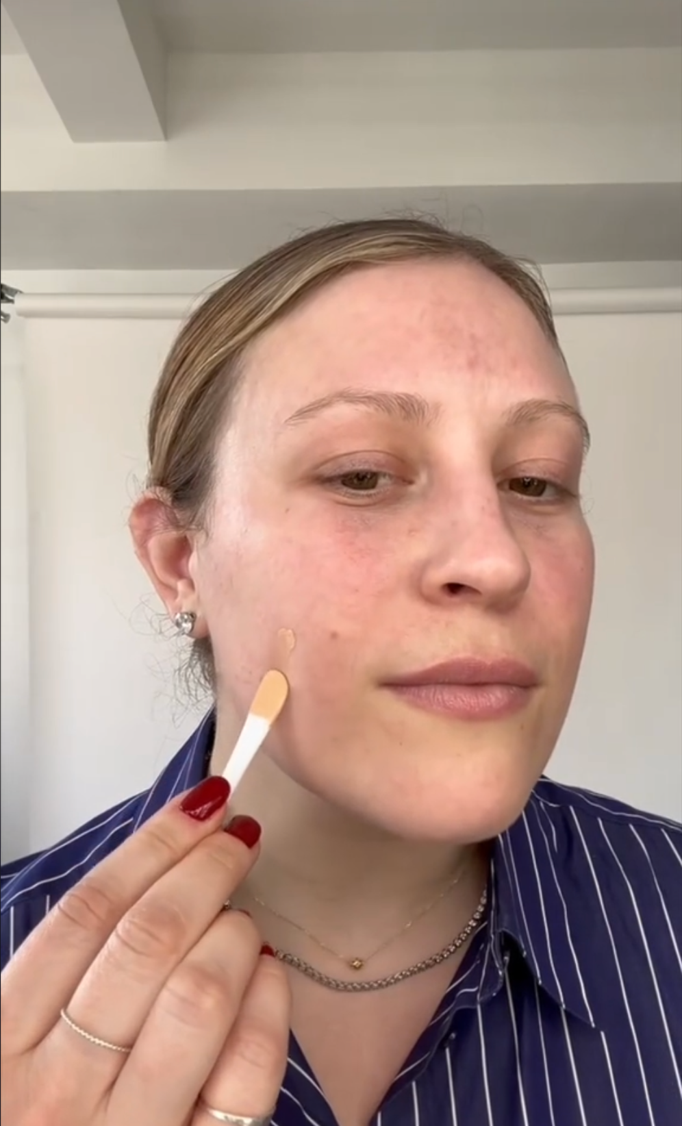 a woman applying boldhue foundation to her face