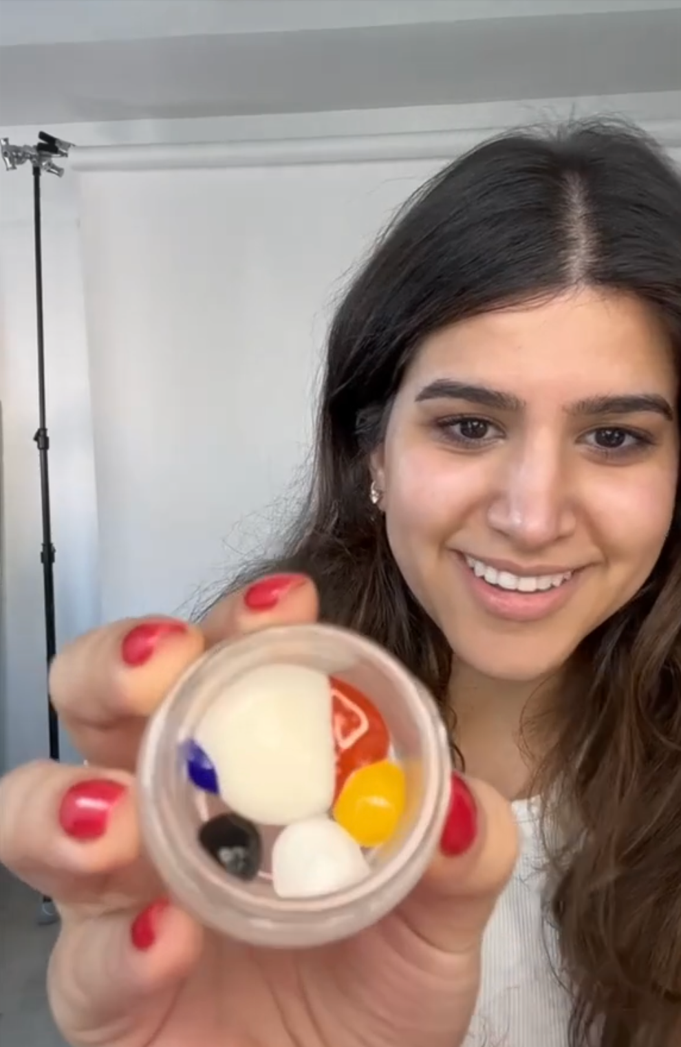 a woman showing her unmixed pigments in a jar and smiling at the camera